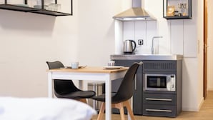 Cocina compacta con microondas, hervidor y armarios.