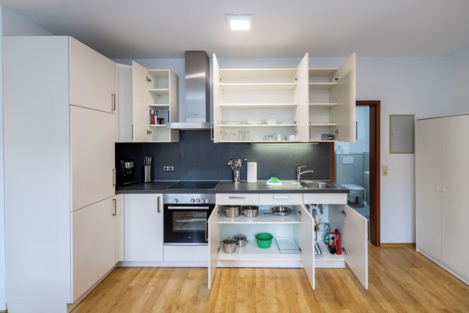 A compact kitchen with white cabinets, a built-in oven, and a sink.