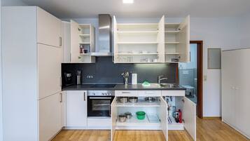 A compact kitchen with white cabinets, a built-in oven, and a sink.