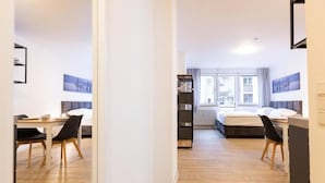 Habitación de hotel moderna con suelo de madera, una cama, un escritorio con silla y un armario.