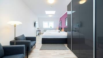 A modern bedroom with a bed, a sofa, a floor lamp, and a large window.