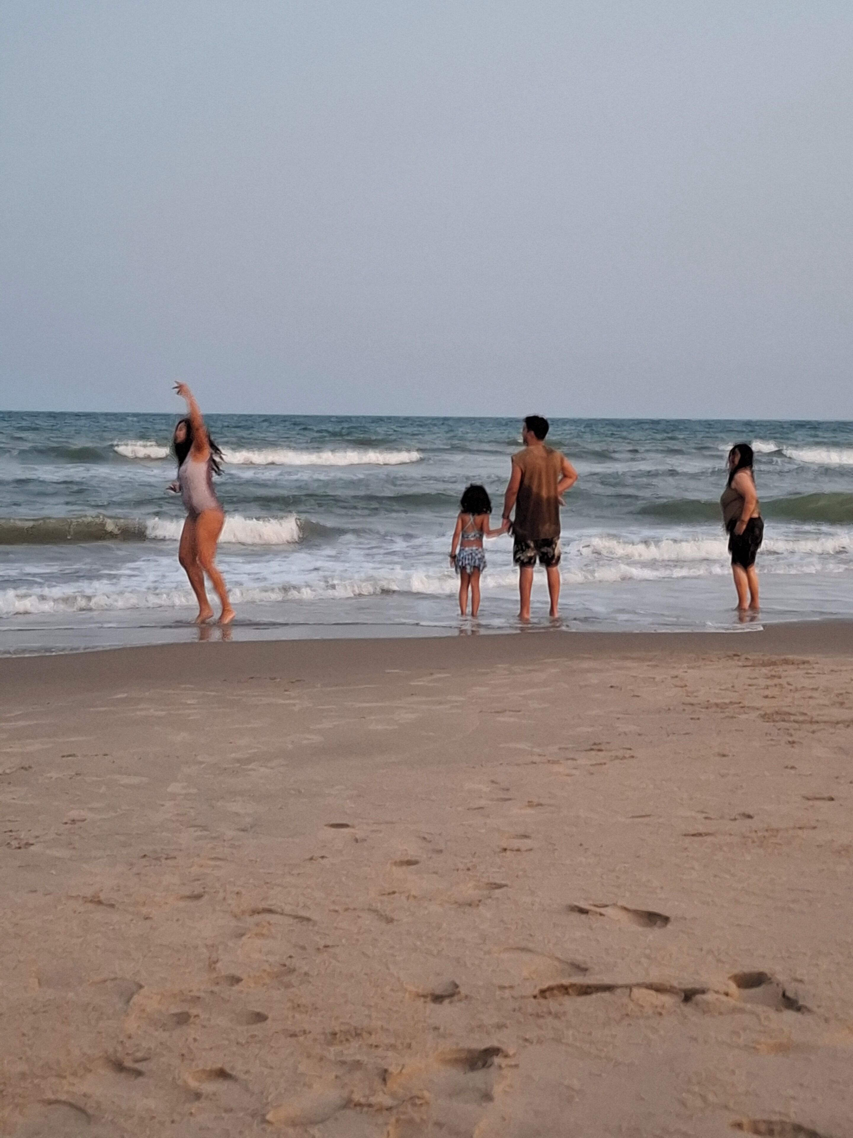 Une plage de sable où l’on peut voir des empreintes de pas qui mènent à l’eau.