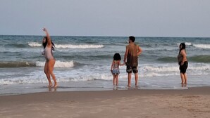 Une plage de sable où l’on peut voir des empreintes de pas qui mènent à l’eau.