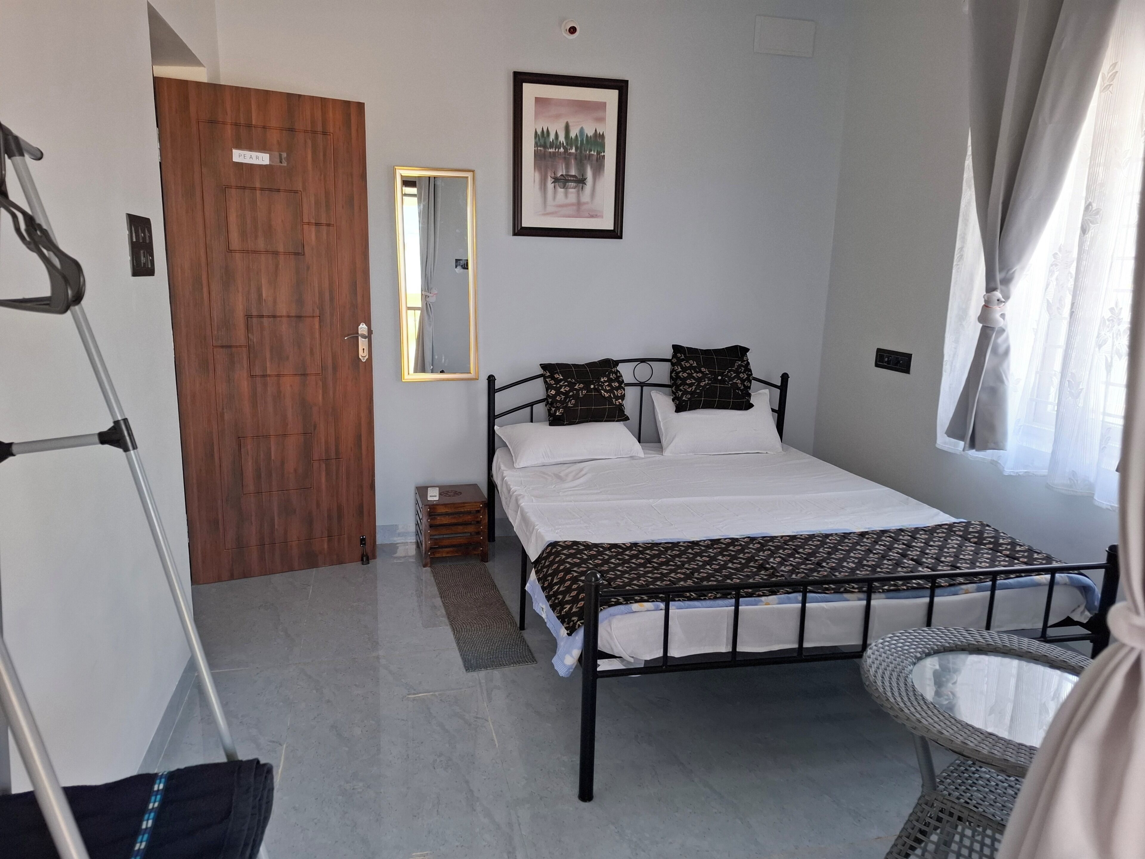 Een slaapkamer met een bed, spiegel, deur en een rieten stoel.