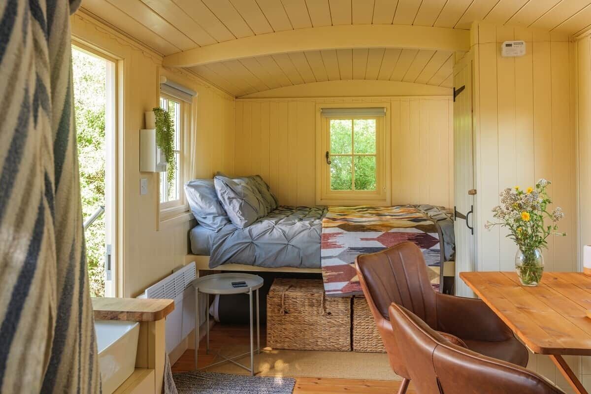 A compact room with a bed, a small table, a chair, and a window.