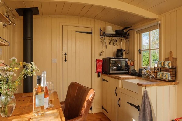 Un intérieur en bois comprenant un coin cuisine, une table à manger agrémentée d’un vase de fleurs et une chaise.