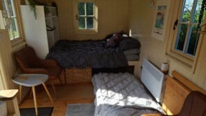 Een kleine kamer met een bed, een tafeltje, een stoel en een radiator.