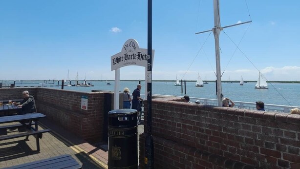 Een restaurant aan het water met een bordje 'White Hart Hotel' en zicht op zeilboten.