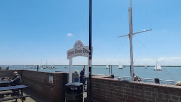 A waterfront restaurant with a sign for 'White Hart Hotel' and a view of sailboats on the water.