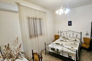 A bedroom with a bed, a window with blinds, a chandelier, and a chair. - A cozy villa with all the amenities and an outdoor gazebo. (Puglia)