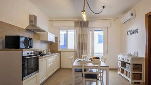 A modern kitchen with white cabinetry, a built-in oven, a microwave, and a dining area with a table and chairs. - A cozy home in a quiet part of town, 200 meters from the sea as the crow flies (Marettimo)