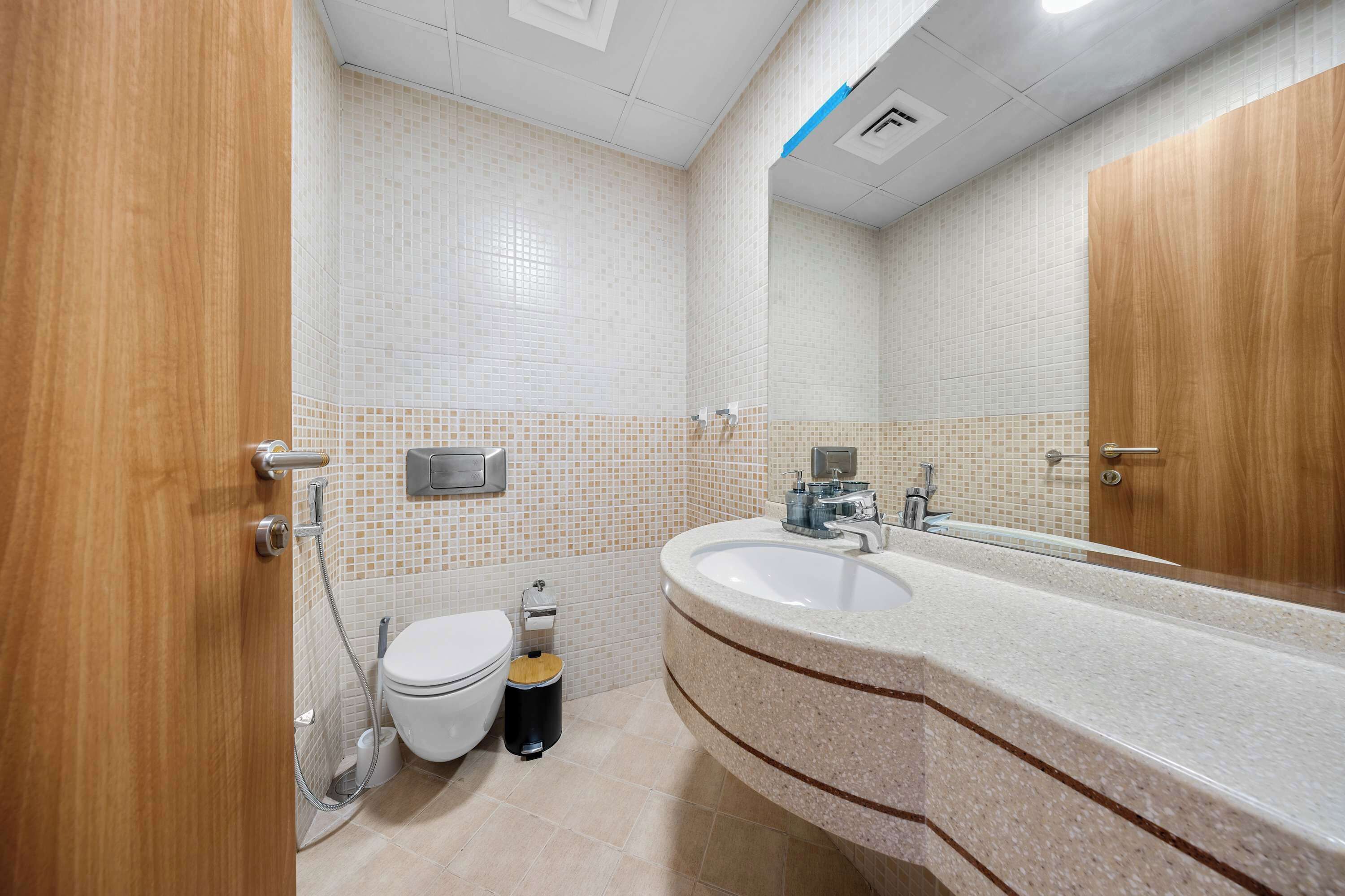 Une salle de bain équipée de toilettes, d’un bidet, d’un lavabo et d’un miroir.