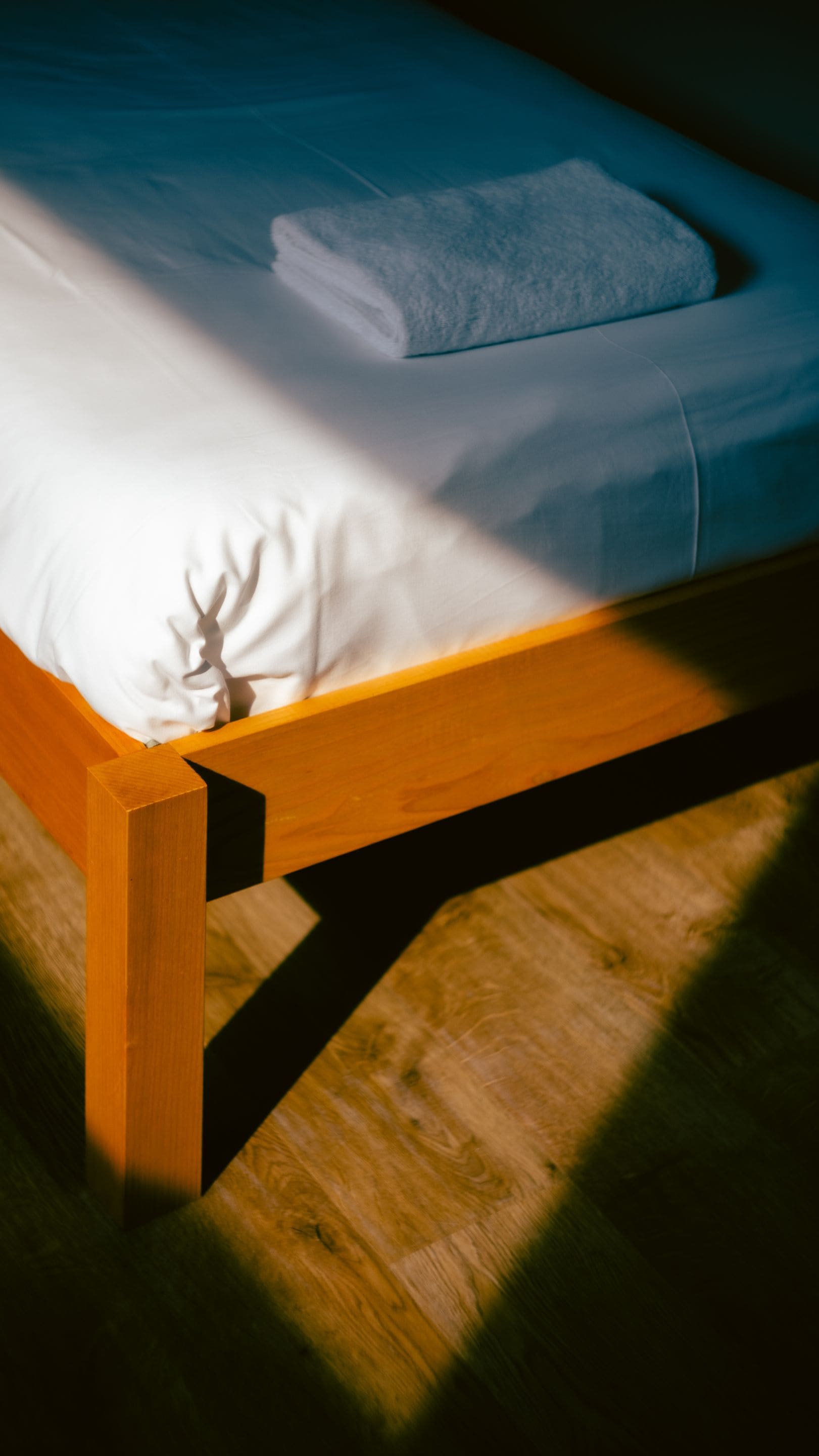 A bed with a wooden frame and white bedding.