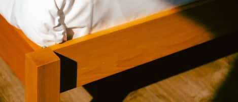 Una cama con estructura de madera y ropa de cama blanca.