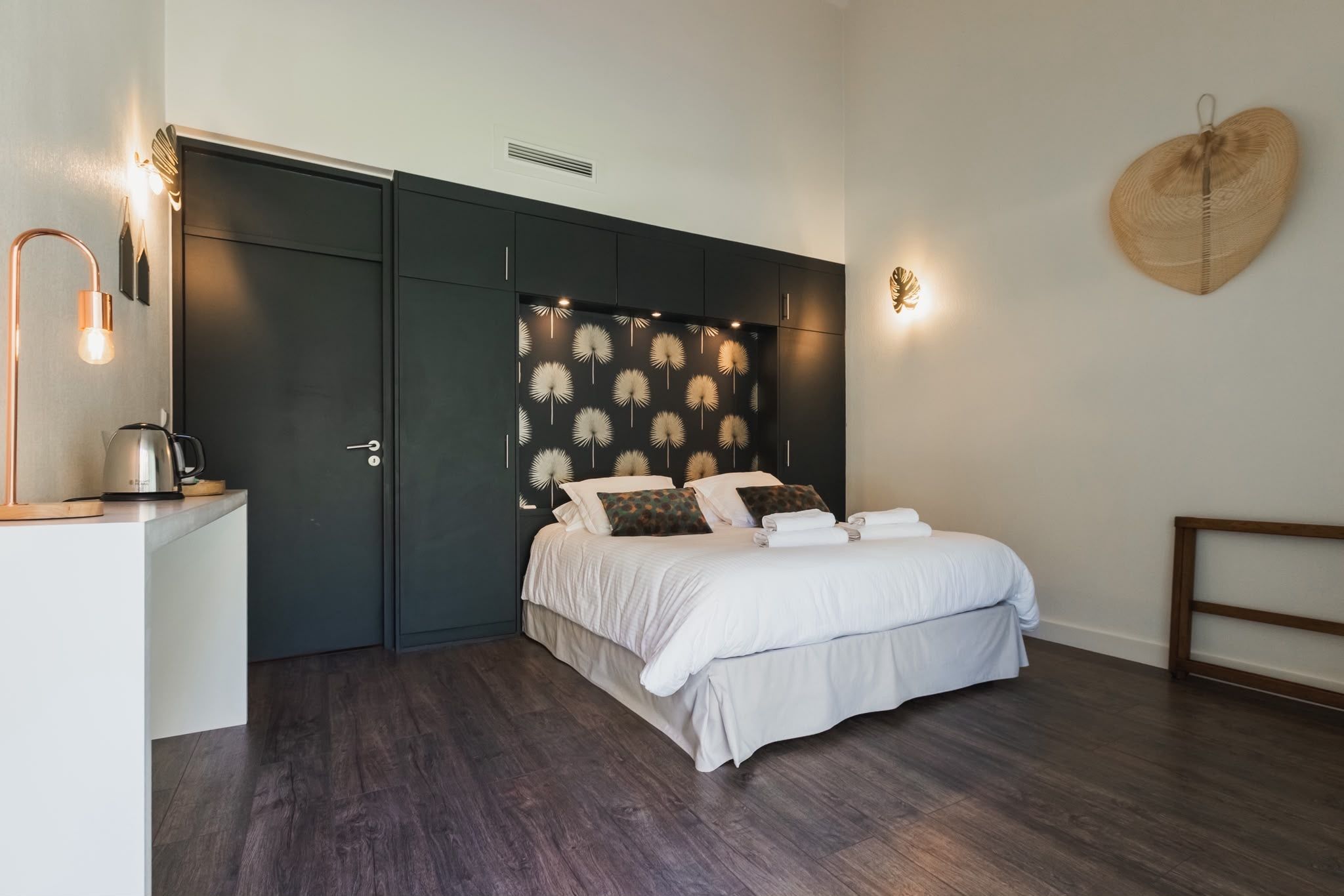 A bedroom with a bed, bedside tables, a wardrobe, and a decorative wall panel.