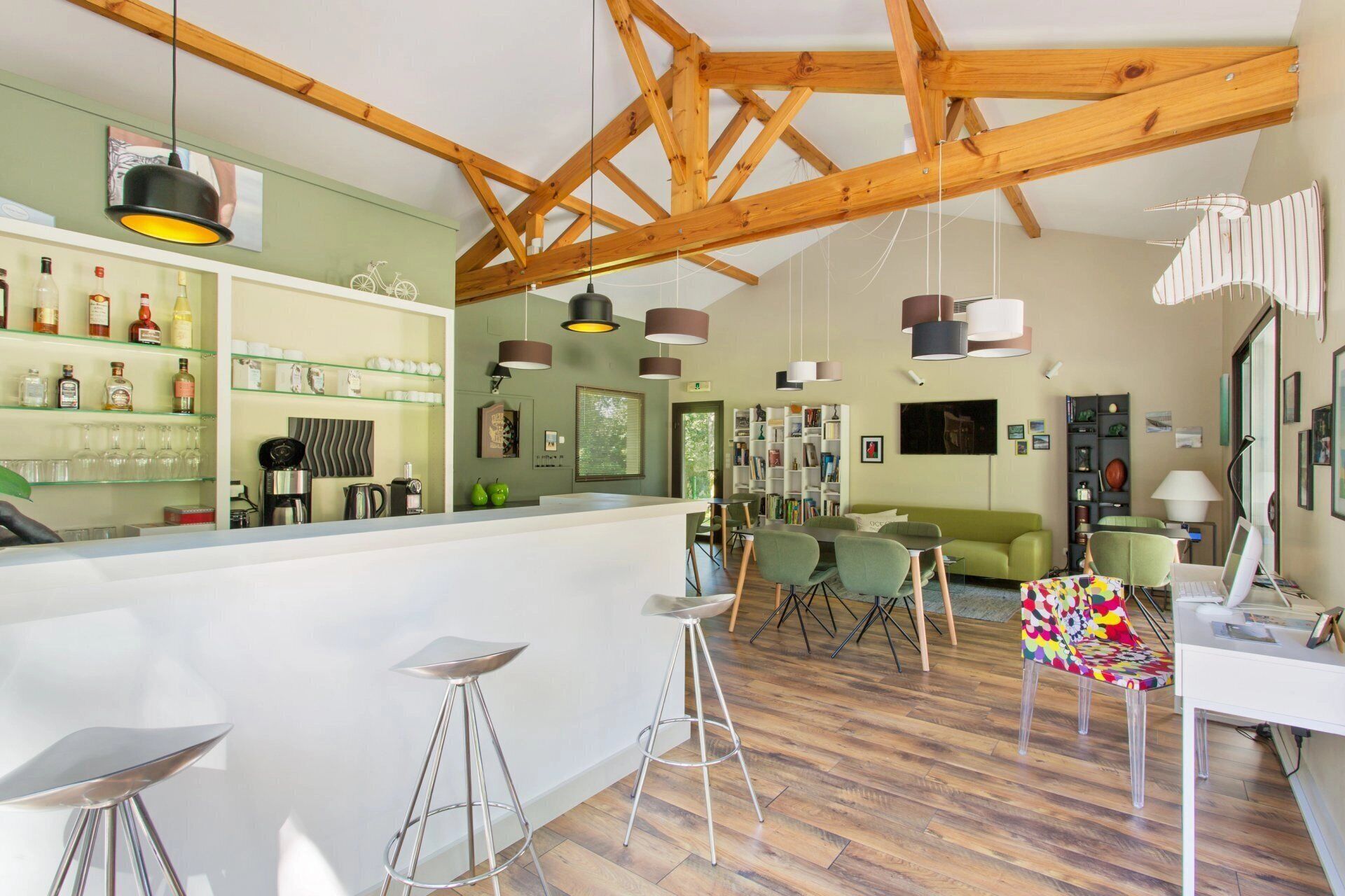 Un intérieur moderne avec des poutres apparentes, un coin bar doté d’étagères et un espace salon avec des chaises et un canapé.