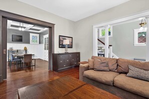 A living room with a sofa, a coffee table, and a dining area with a table and chairs. - Relaxing retreat with hot tub near Cherokee Park! (Louisville)