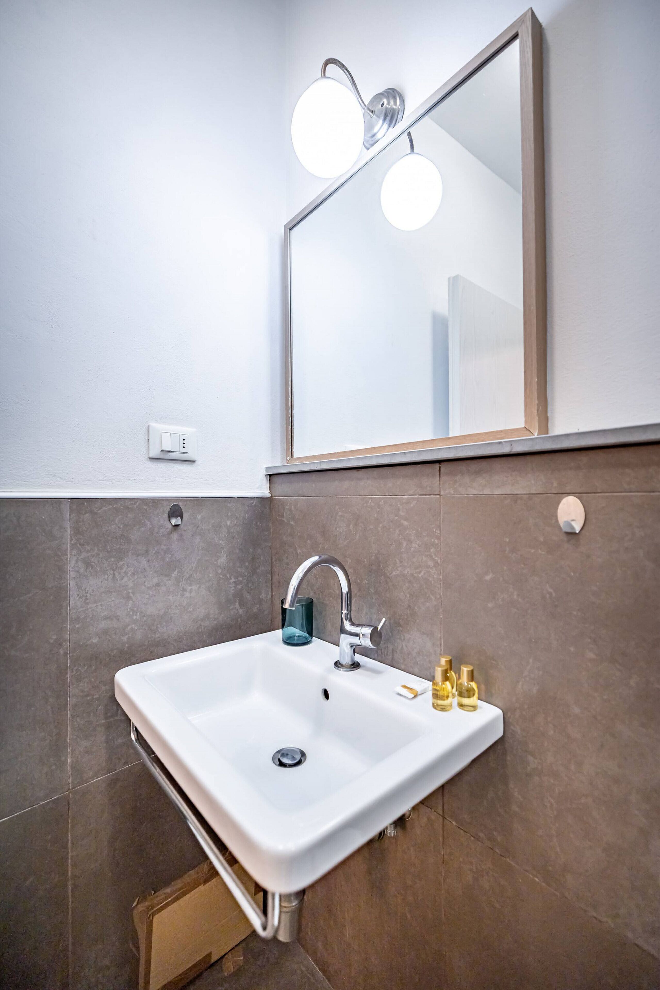 A bathroom with a white sink, a mirror, and a light fixture above it.