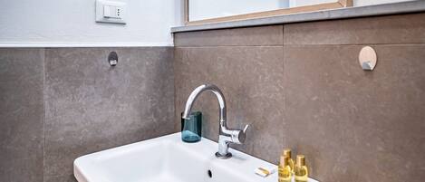 A bathroom with a white sink, a mirror, and a light fixture above it.