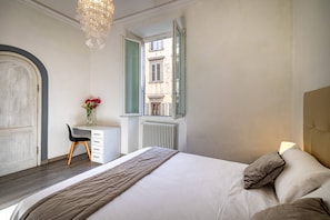 Een slaapkamer met een bed, een bureau en een raam.
