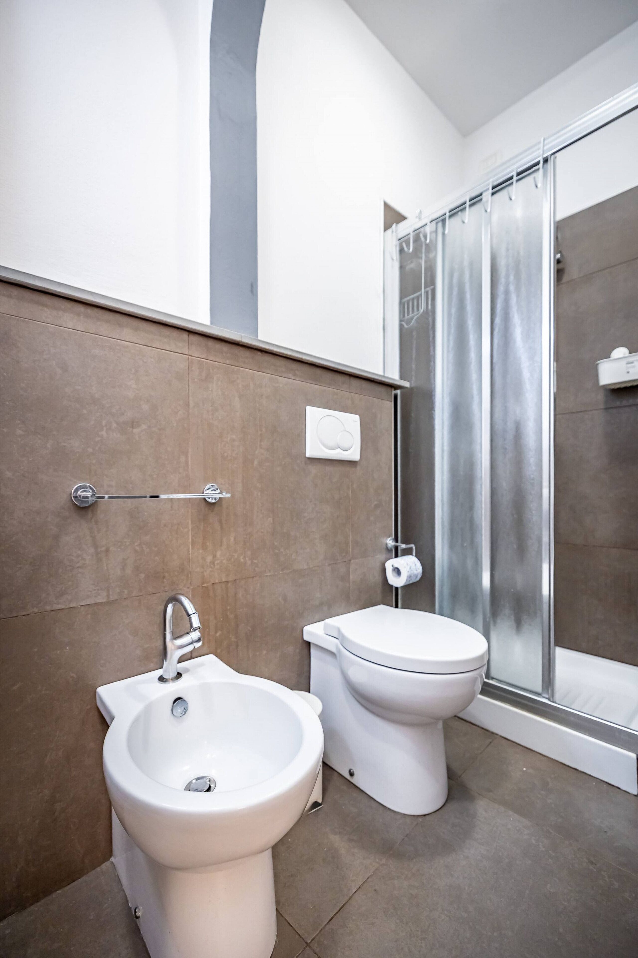 A modern bathroom with a bidet, toilet, and a glass shower enclosure.