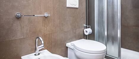 A modern bathroom with a bidet, toilet, and a glass shower enclosure.