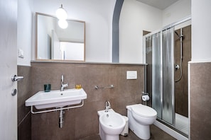 Een badkamer met een wastafel, toilet, douche en bidet.