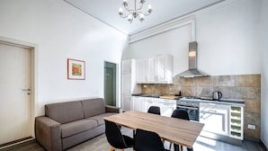 A modern kitchen with white cabinets, a wooden dining table, and black chairs. - Proconsolo A (Florence)