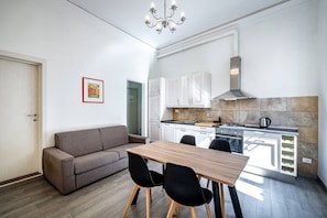 Une cuisine moderne avec des meubles blancs, une table à manger en bois et des chaises noires.