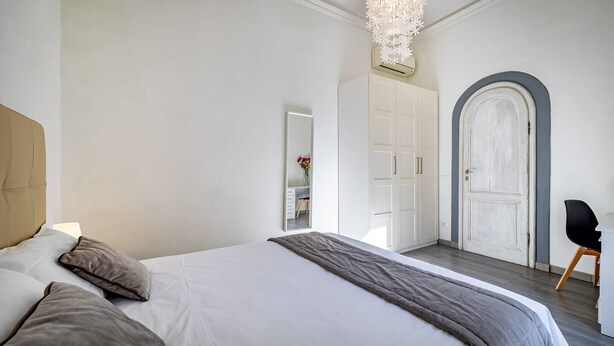 A bedroom with a large bed, a wardrobe, a mirror, and a door. - Proconsolo A (Florence)