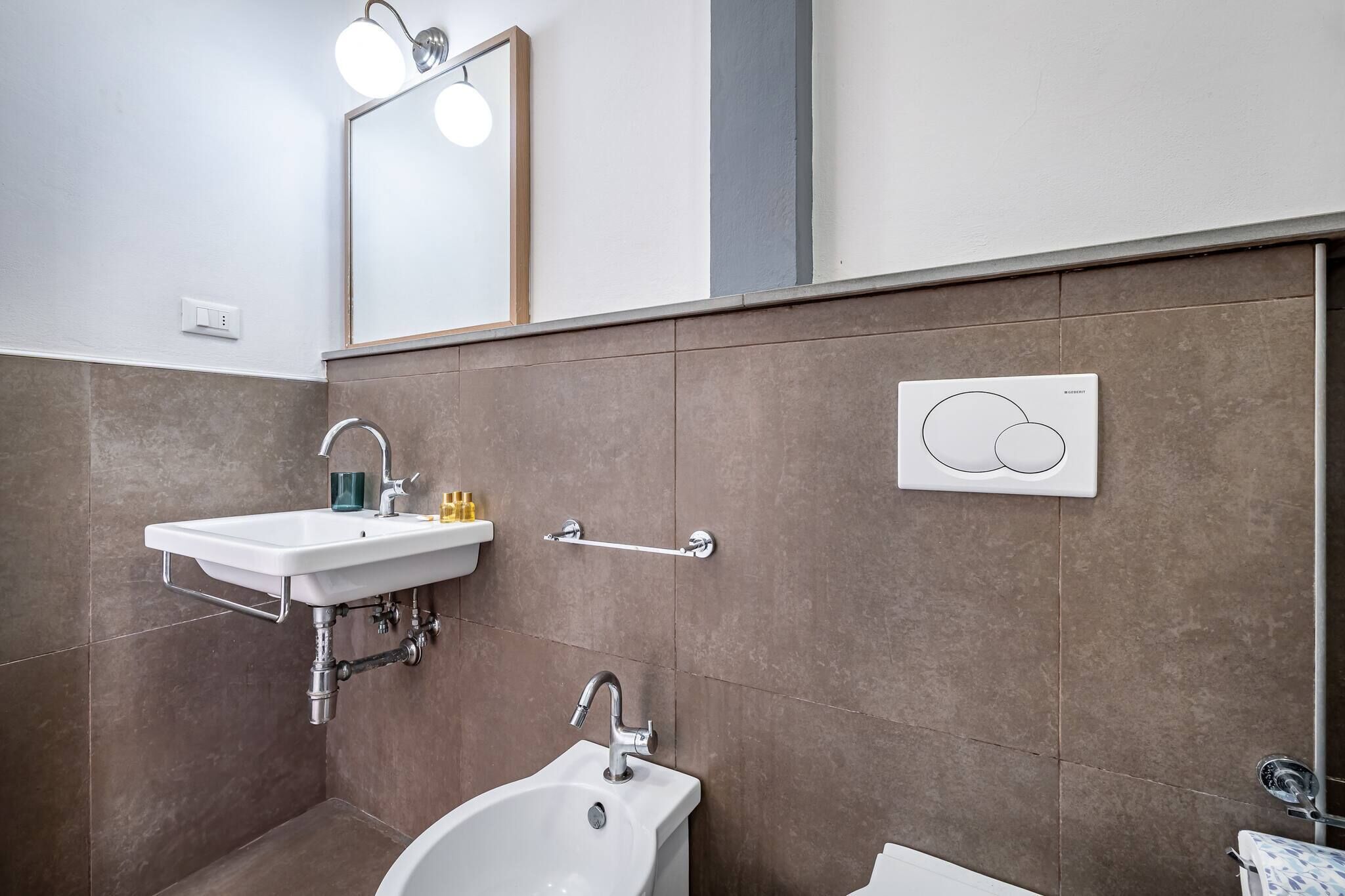 Une salle de bain moderne avec un lavabo blanc, une baignoire et un miroir avec éclairage intégré.