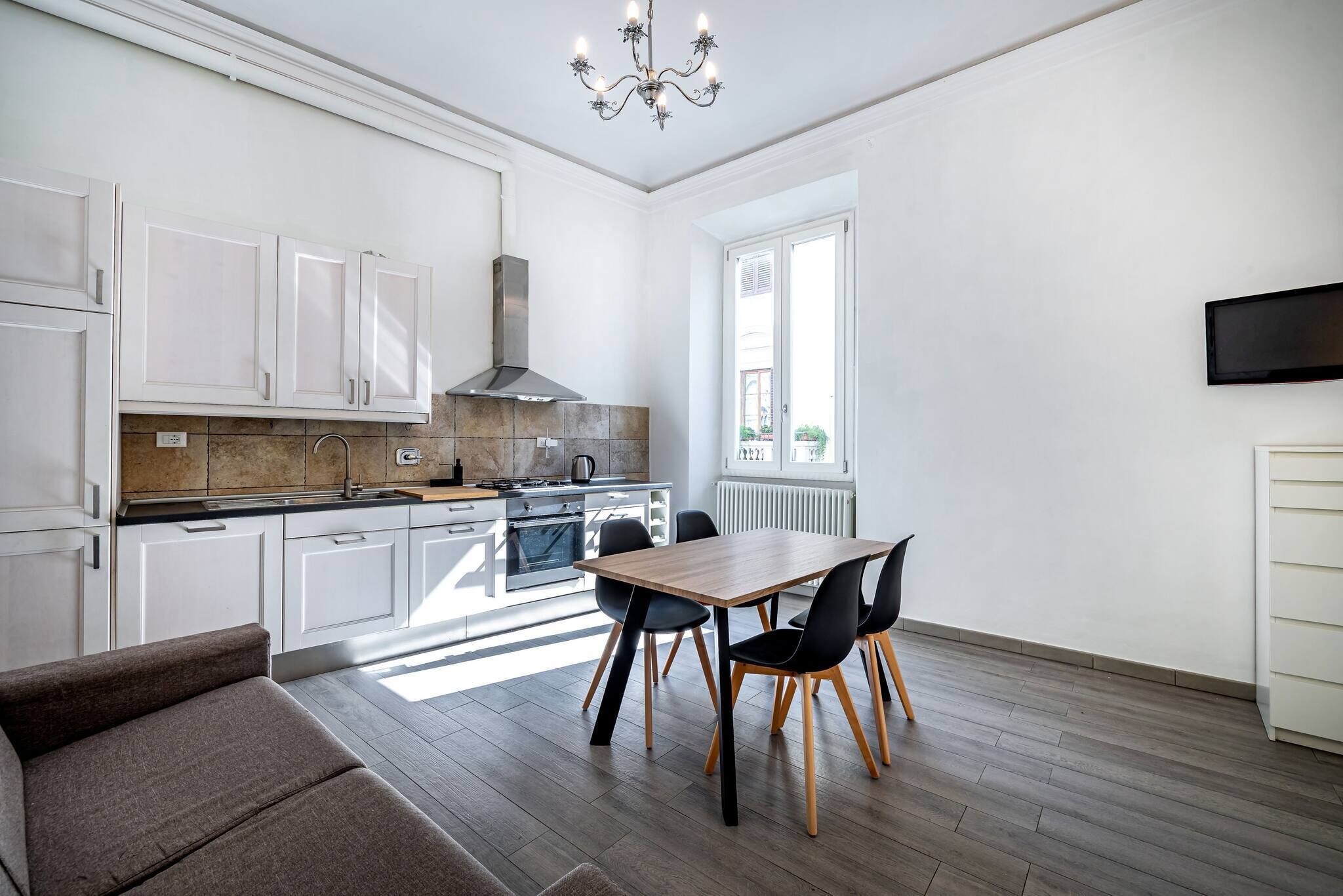 A modern kitchen with white cabinets, a dining table with chairs, and a chandelier.