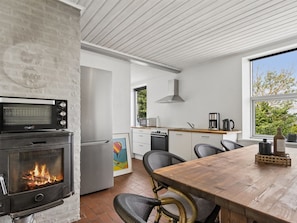 Eine moderne Küche mit Holzofen, Mikrowelle, Kaffeemaschine und Blick ins Freie.