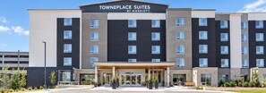 Un hotel de varios pisos con un diseño moderno, que presenta una entrada destacada con un corredor cubierto y un letrero que dice 'Towneplace Suites by Marriott'.