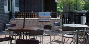 An outdoor patio area with a barbecue grill, wicker furniture, and a stone wall.
