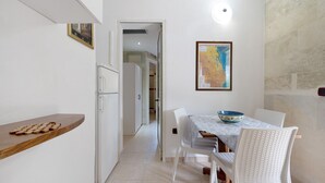 A dining area with a table, chairs, a bowl, and a refrigerator. - Tiny Home 'Atenaion Otranto' with Outdoor Space (Otranto)