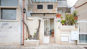 A building with a gated entrance, potted plants, and a visible balcony. - Tiny Home 'Atenaion Otranto' with Outdoor Space (Otranto)