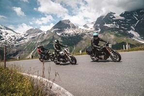 Deux motocyclistes sur une route asphaltée, avec un paysage montagneux en arrière-plan.