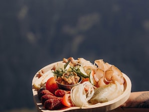 Un grand plateau en bois garni de divers aliments, notamment des saucisses, du fromage et des cornichons.