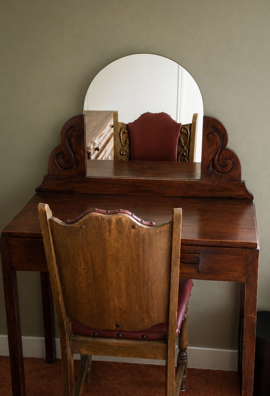 A wooden desk with a mirror and a chair.