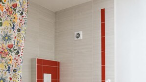 A bathroom with a toilet, a handrail, and a shower curtain.