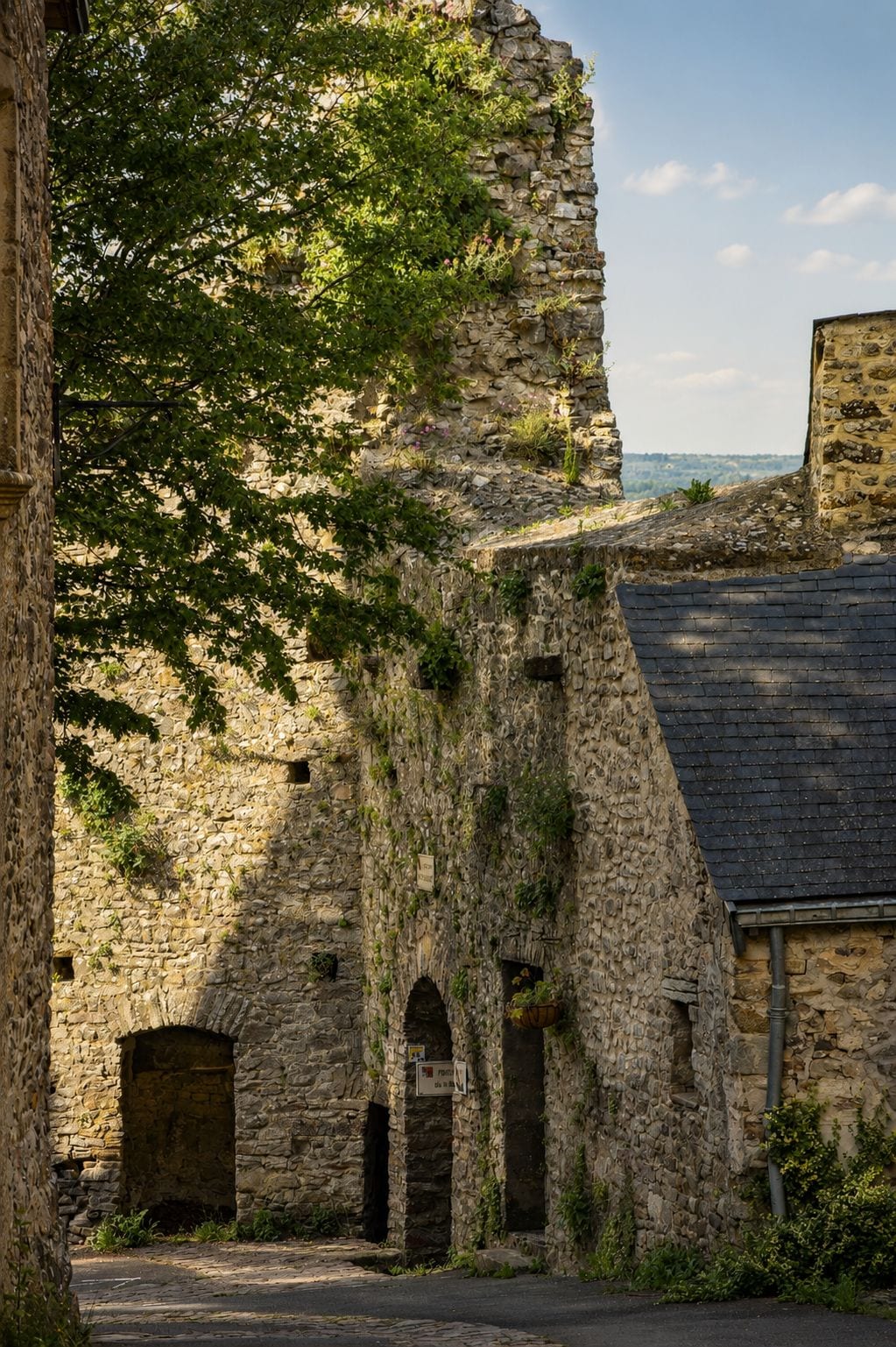 A stone building with arched doorways and a steep, rocky cliff.