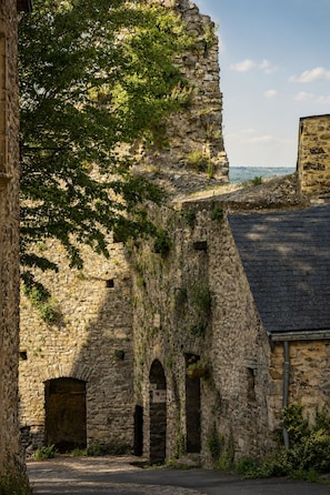 Un bâtiment en pierre, doté d’arcades et situé au pied d’une falaise abrupte et rocheuse.