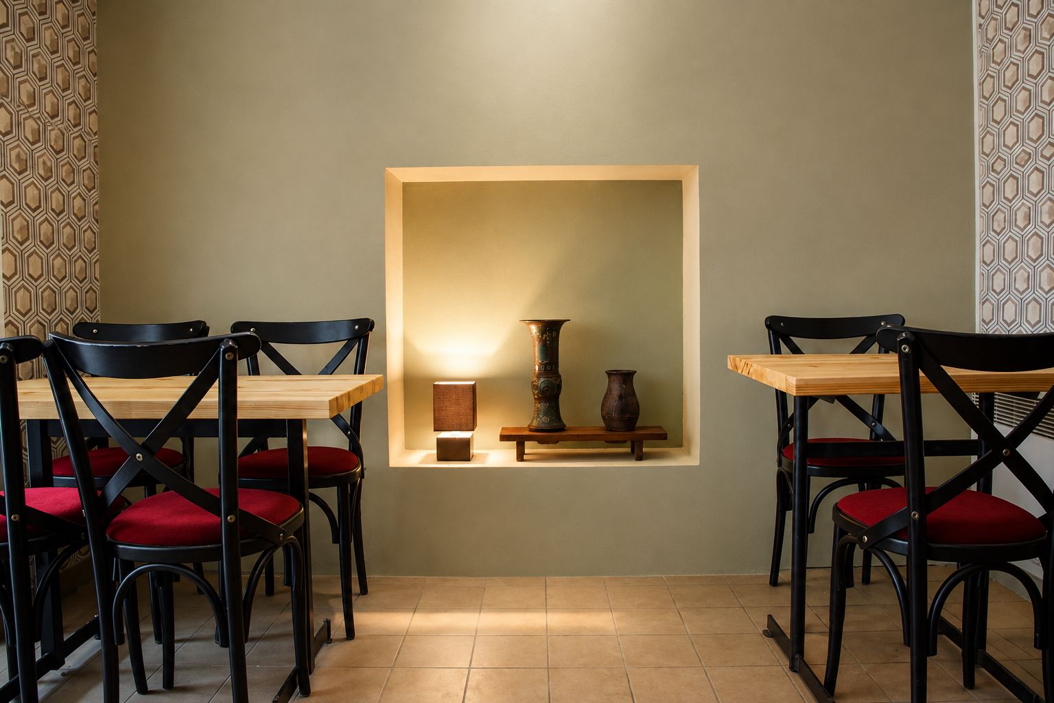 Un comedor con una mesa y sillas, un estante de pared con adornos, y papel tapiz estampado.