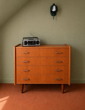 Une commode en bois avec des tiroirs et une radio posée sur le dessus.