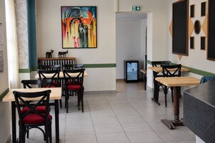 Un interior de restaurante con varias mesas y sillas, un cuadro en la pared y un refrigerador.