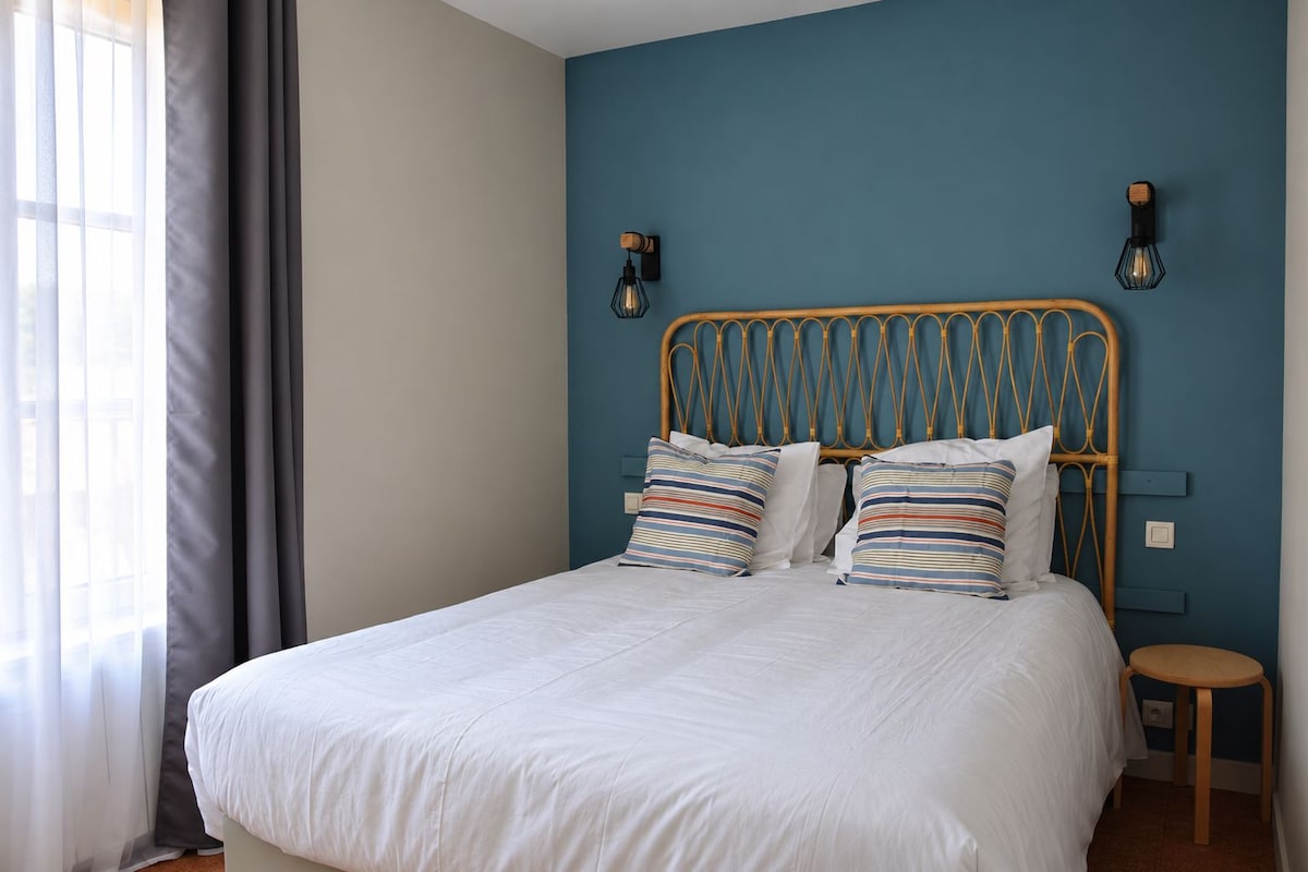 A bed with a white mattress and striped pillows, a wooden headboard, and two wall-mounted light fixtures.