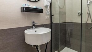 Un baño moderno con cabina de ducha de vidrio, un lavabo blanco y un espejo redondo.
