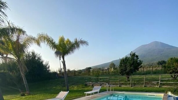 Piscina con sillas de descanso y vista a la montaña.