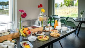 Un bufé de desayuno con diversas opciones de comida, un bol de fruta y vistas al exterior.